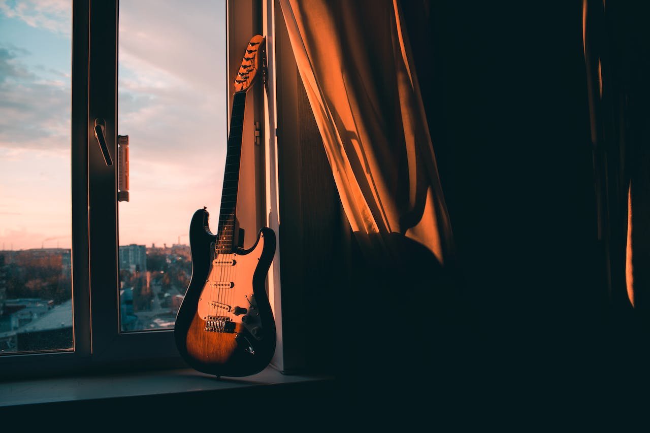 A cheap electric guitar sitting on a windowsill