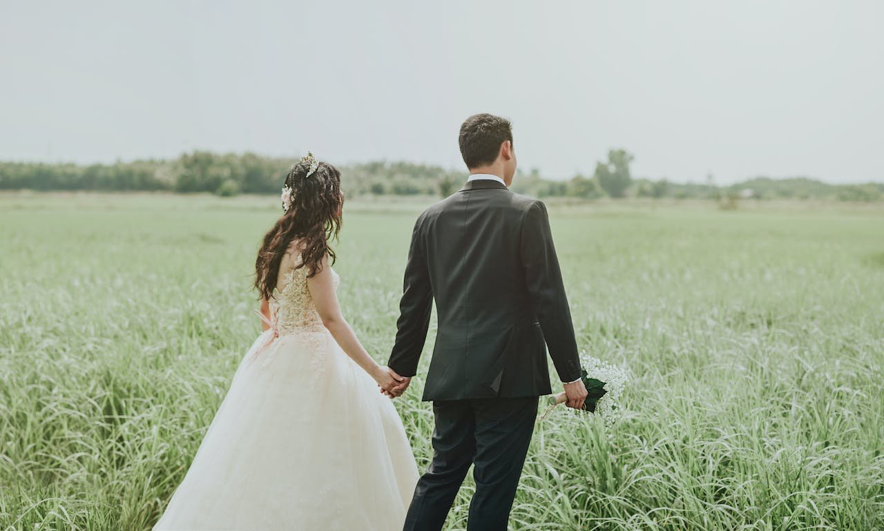 A just-marred couple walking in a field during the day