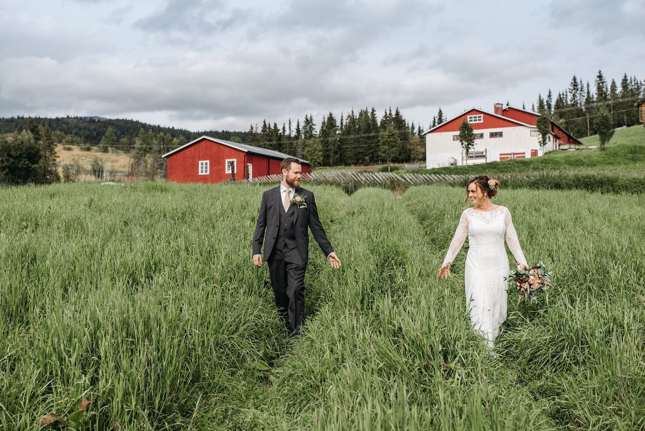 A couple at a wedding walking through a rural field